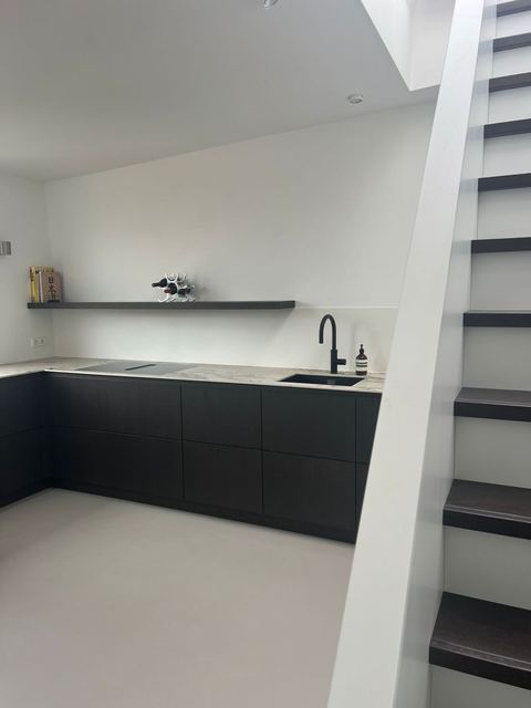 Küche mit dunklen Fronten und Treppe ins obere Geschoss der Maisonette