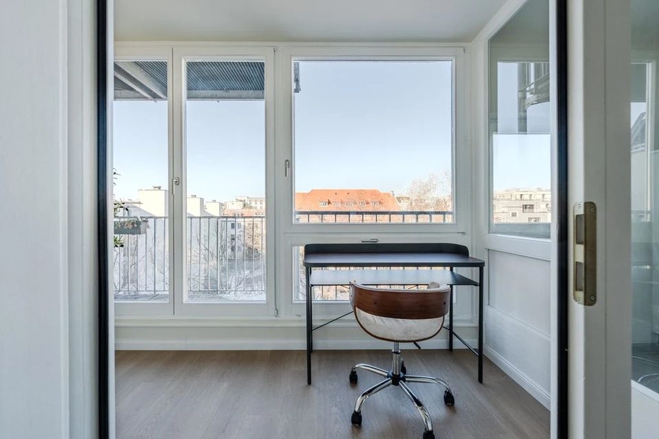 Helles Zimmer mit Fensterfront und Blick über die Dächer