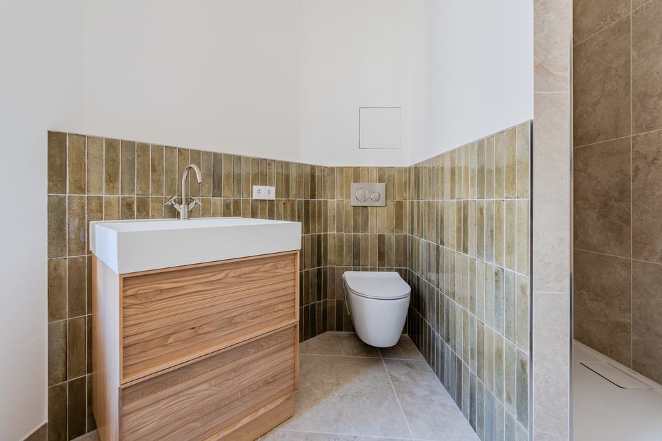 Bad mit grünen Wandfliesen, Holz-Waschtisch und Wand-WC